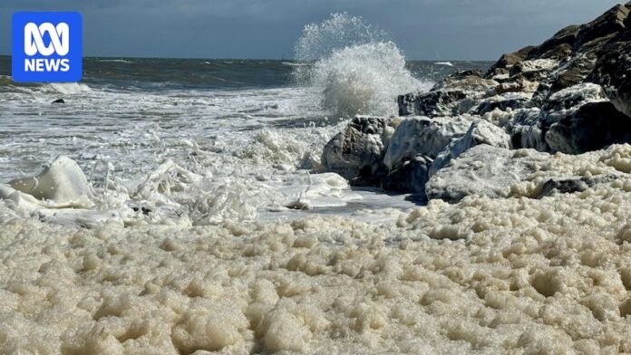 White sea foam covering concrete stairs at Glenelg beach. 